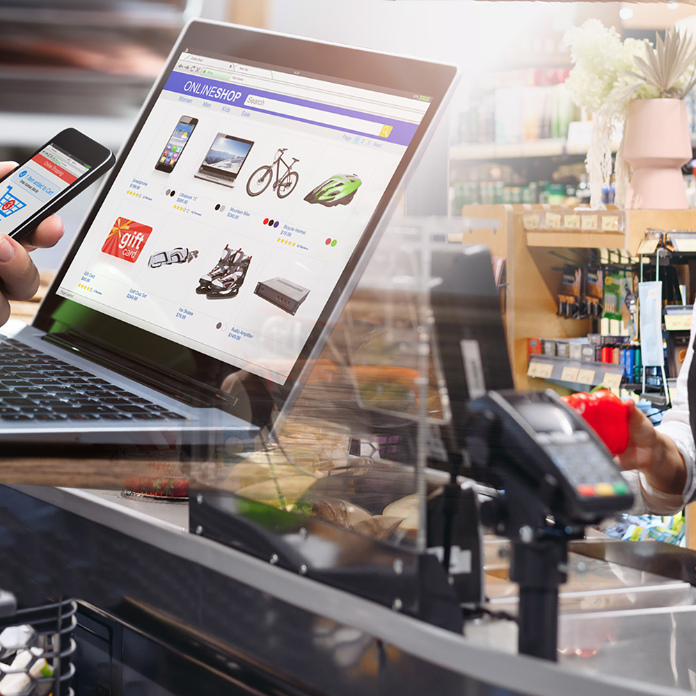 Laptop mit Angeboten neben Kasse im Supermarkt